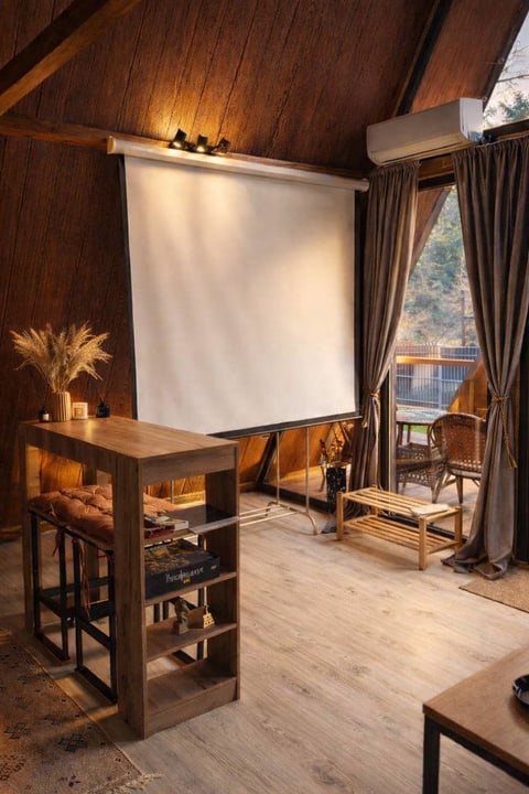 Интерьер A-frame домика «Грань» с проектором и панорамным окном.