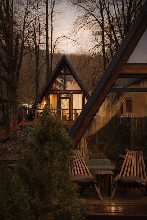 A-frame домик «Грань» вечером среди деревьев в Красной Поляне.